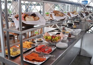 Un bufé con diversas opciones de comida, incluyendo frutas, verduras y pan.