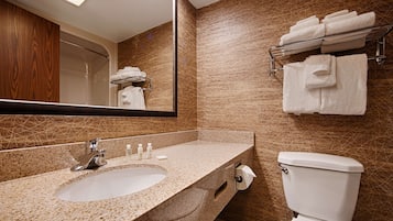 A bathroom with a granite sink, a toilet, and a towel rack with folded towels.
