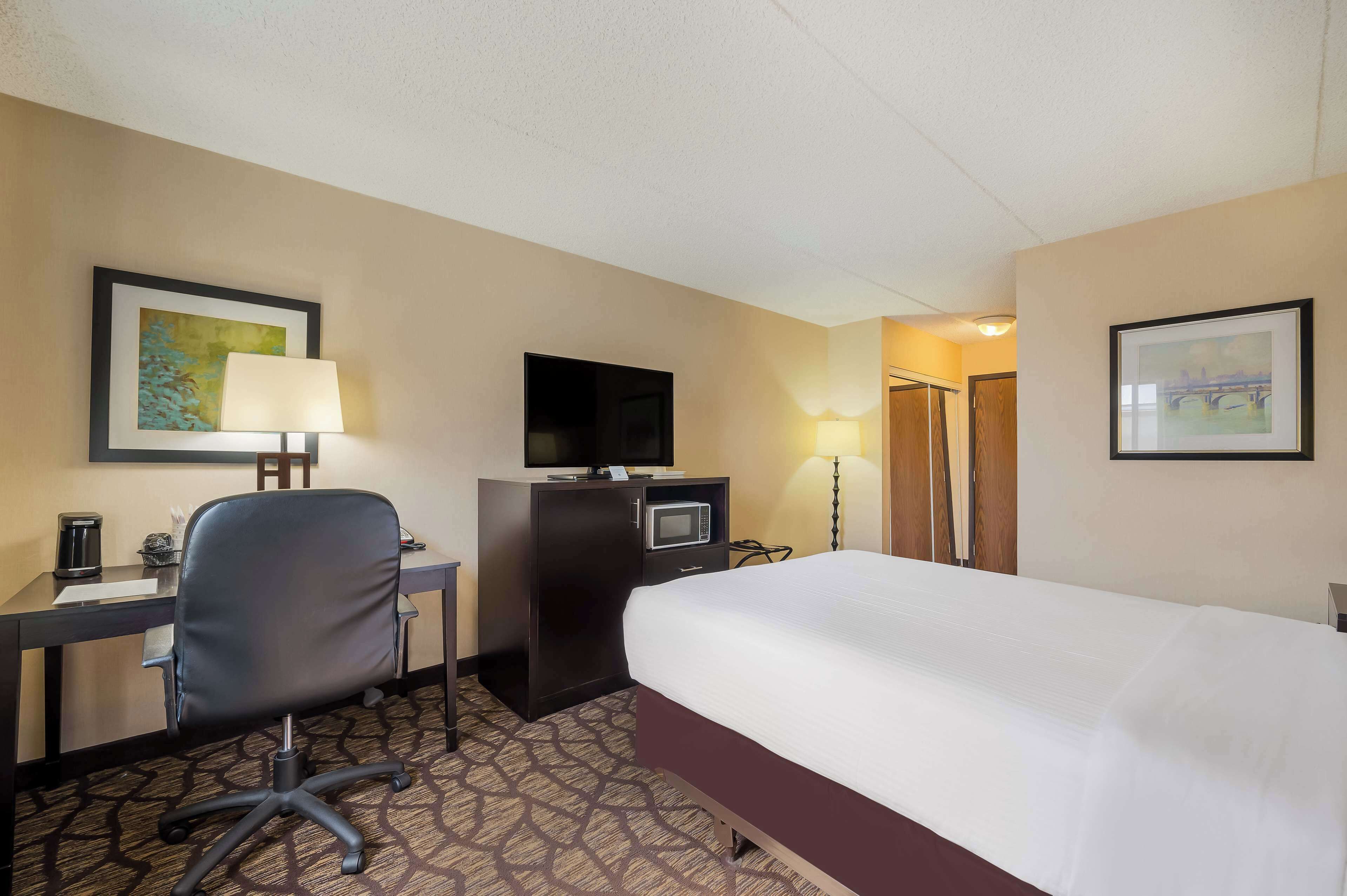 Une chambre d’hôtel équipée d’un lit, d’un bureau, d’une chaise, d’une télévision, d’un four à micro-ondes et de deux lampes.