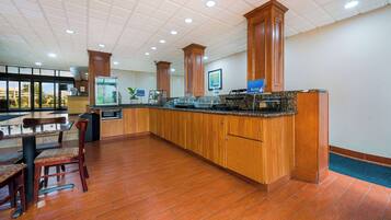 A spacious kitchen area with wooden cabinets, a granite countertop, and a dining table with chairs.