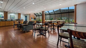 A spacious indoor area with a high ceiling, large windows, and a variety of seating arrangements including tables and chairs. - Best Western Detroit Livonia (Livonia)