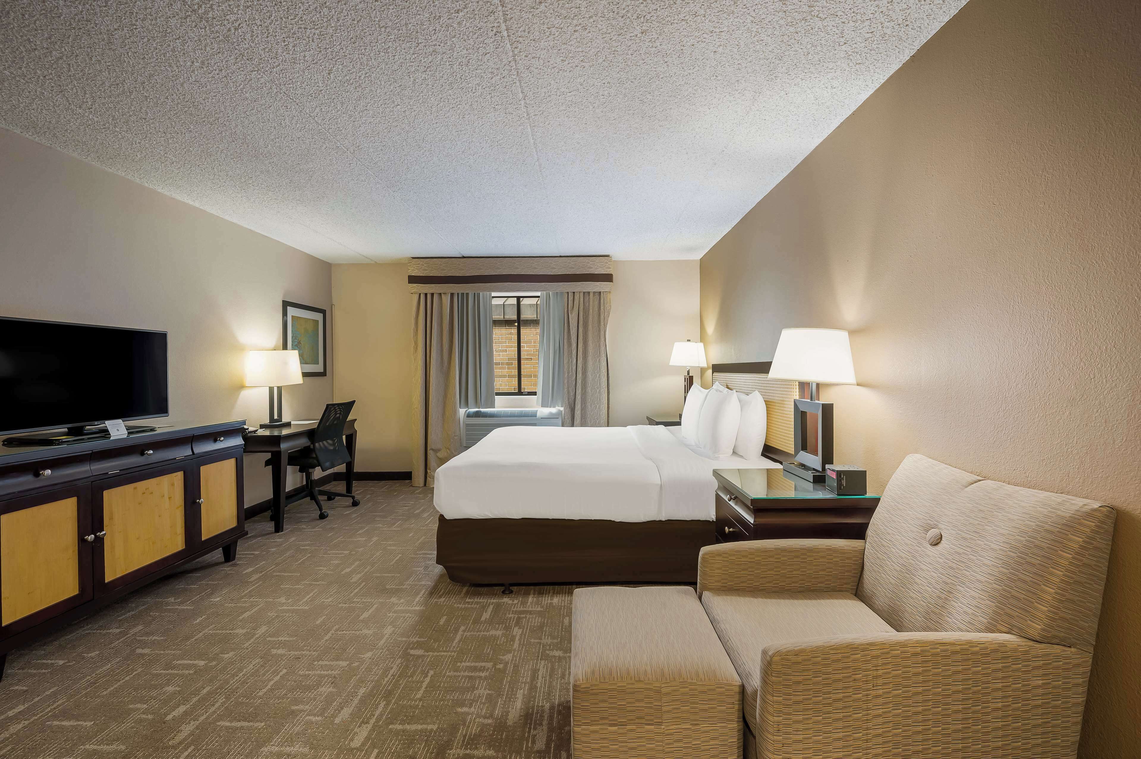 A hotel room with a bed, a desk, a TV, and a sofa.