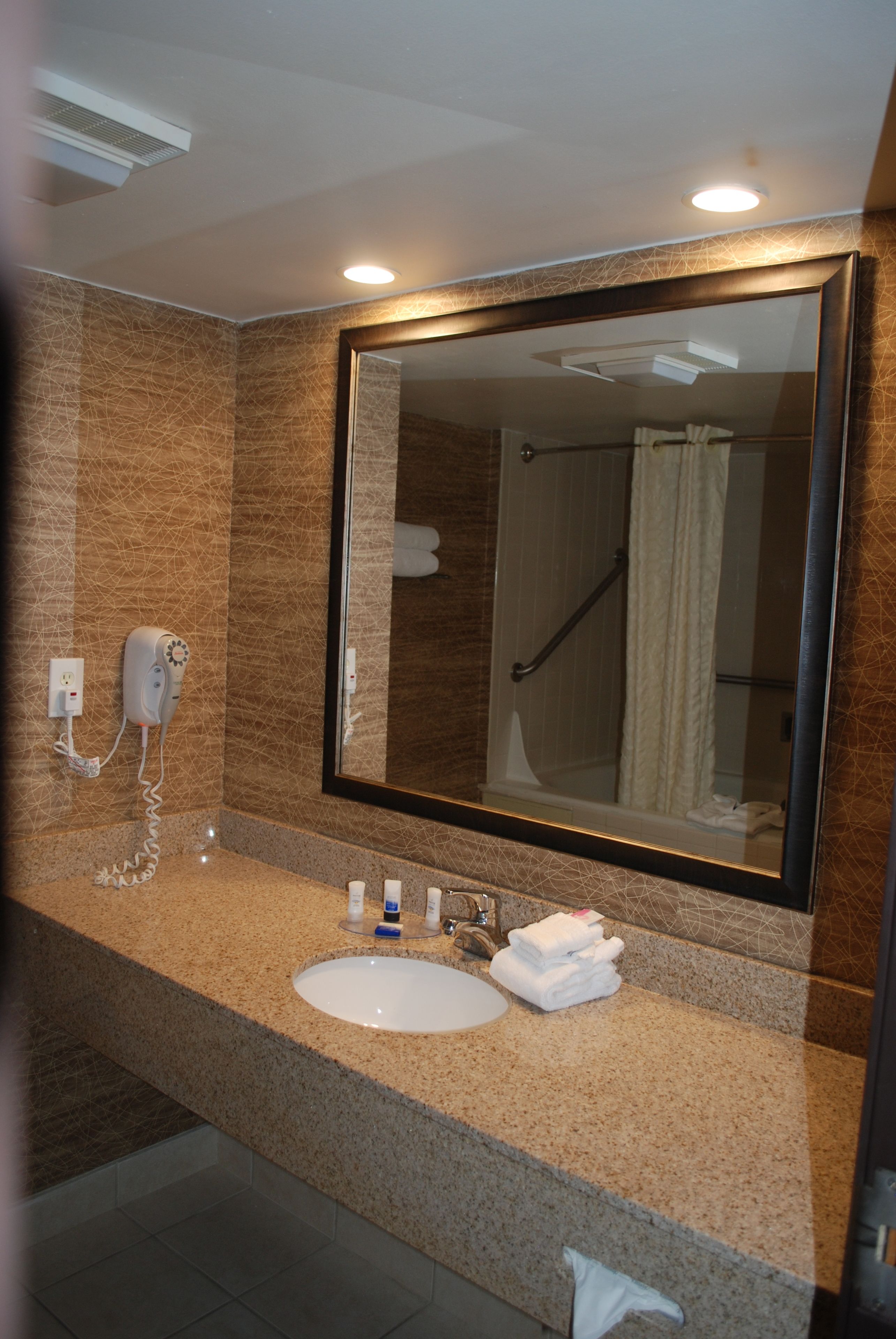 A bathroom with a sink, mirror, hairdryer, and towel rack.