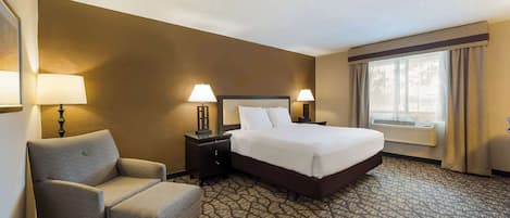 A hotel room with a bed, two bedside tables with lamps, a chair, and a patterned carpet.