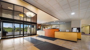 A reception area with a reception desk, a large window, and a view of the outdoors. - Best Western Detroit Livonia (Livonia)