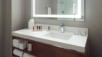 A modern bathroom with a white sink, a large mirror, and a wooden vanity.