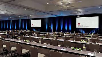 A conference room with rows of tables, chairs, and a large screen displaying the Marriott University of Dayton logo.