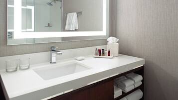 Un baño moderno con un espejo grande, lavamanos blanco y un perchero para toallas.