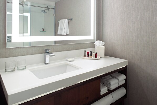 Un baño moderno con un espejo grande, lavamanos blanco y un perchero para toallas.