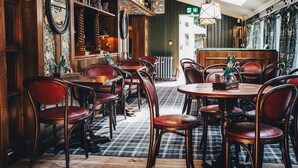 Un restaurante acogedor con muebles de madera, suelo a cuadros y una zona de bar.