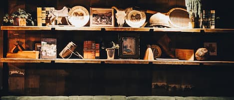 A cozy room with a green upholstered sofa and wooden shelves filled with various items like books, plates, and framed pictures.
