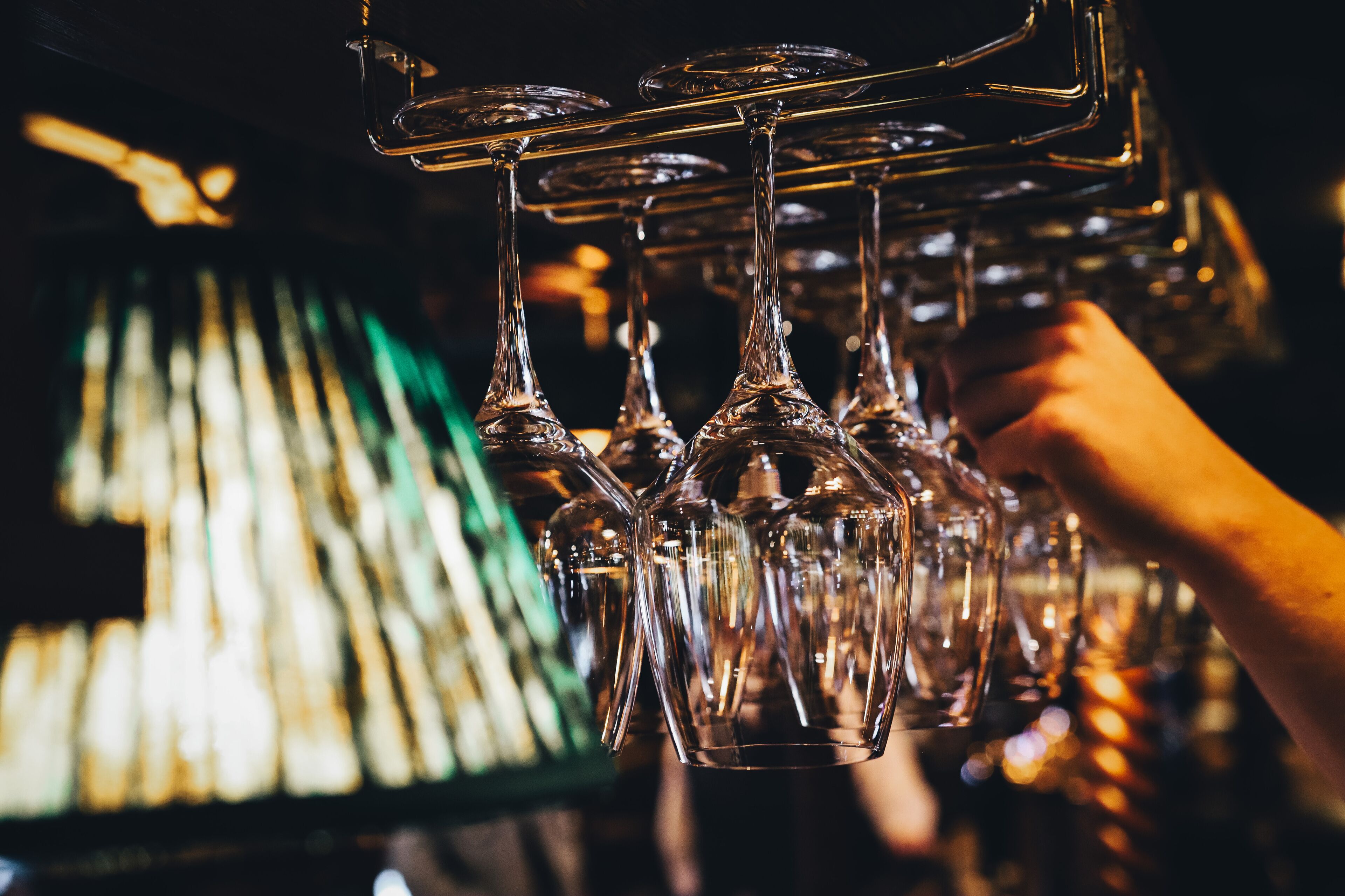 A hand holding a rack of wine glasses.