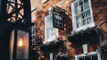A brick building with a pub sign, windows with white frames, and hanging flower baskets.