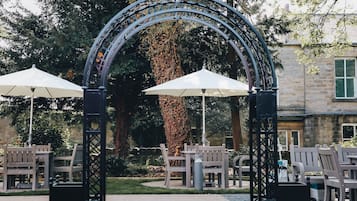 Un espacio al aire libre con un arco de metal, bancos y sombrillas.