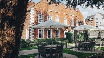 A courtyard with outdoor seating and a brick building in the background.