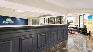 A reception area with a dark reception desk, a large window, and a view of the outdoors. - Days Inn by Wyndham Rock Hill (Rock Hill)