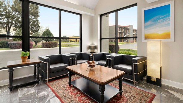 A modern living room with a large window, a sofa set, a coffee table, and a lamp. - Days Inn by Wyndham Rock Hill (Rock Hill)