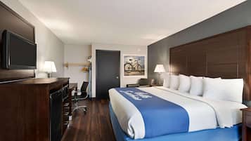Una habitación de hotel con una cama grande, un escritorio con silla, un televisor y una puerta.