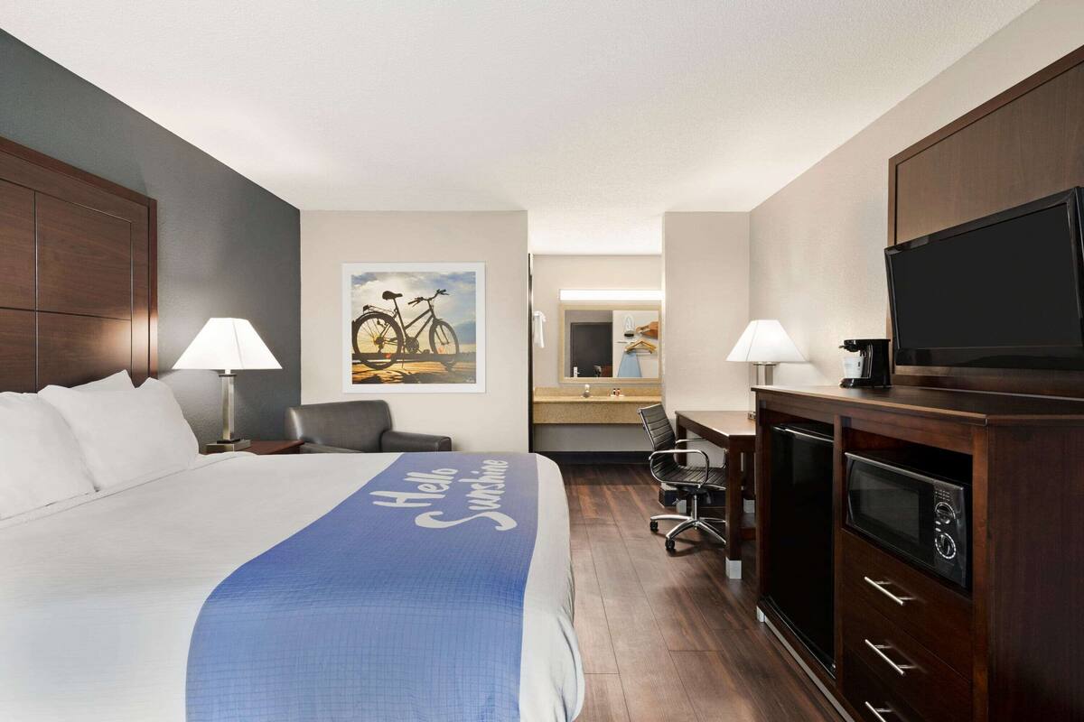 A hotel room with a large bed, a desk with a chair, a television, and a microwave.