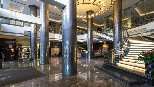 A spacious lobby with high ceilings, large metallic columns, a grand staircase, and a modern chandelier. - Jinglun Hotel Beijing (Beijing)