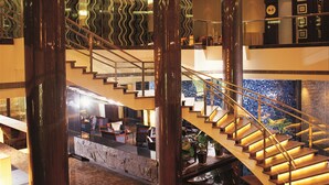 A modern hotel lobby with a central staircase, large pillars, and a patterned ceiling. - Jinglun Hotel Beijing (Beijing)