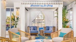 A cozy lounge area with wicker furniture, a central round table, and a decorative archway with a sign. - Margaritaville Resort Cape Cod (Hyannis)