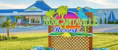 Señal de Margaritaville Resort con palmeras y un ave.