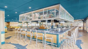 A bar area with a high counter, multiple seating options, and a ceiling with a shark motif. - Margaritaville Resort Cape Cod (Hyannis)