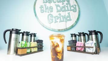 A coffee station with insulated mugs, a thermos, and a sign that reads "Escape the Daily Grind".