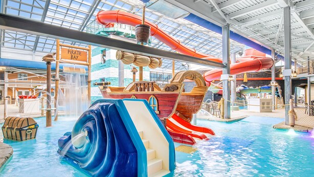 An indoor water park with slides, a pirate-themed ship, and a sign reading "Pirate Bay". - Margaritaville Resort Cape Cod (Hyannis)