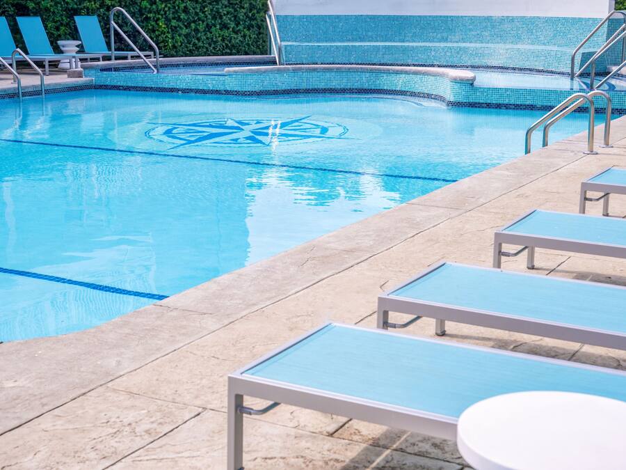 A swimming pool with lounge chairs and a tiled deck.