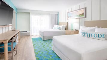 A hotel room with two beds, a desk, a television, and a window with curtains.