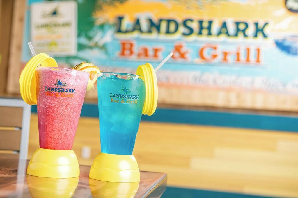 Two Landshark Bar & Grill branded drinks on a table with a blurred background of the establishment.