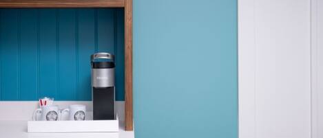 A kitchen area with a coffee maker, two mugs, and a shelf with a model airplane.