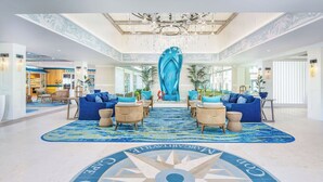 A spacious lobby with a large blue mural, comfortable seating areas, and a prominent circular floor design. - Margaritaville Resort Cape Cod (Hyannis)
