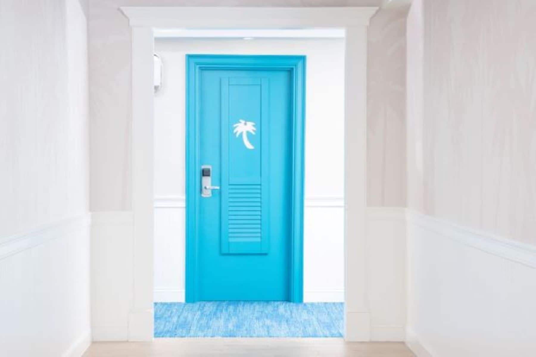 A bright blue door with a palm tree symbol, a keyhole, and a doorbell.