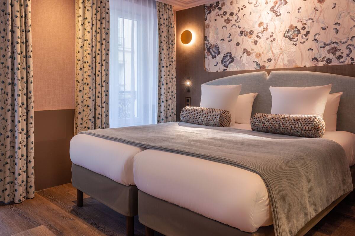 A double bed with a grey headboard, two pillows, and a patterned throw blanket.