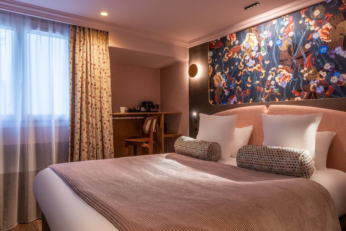 A hotel room with a large bed, a desk, and a chair.