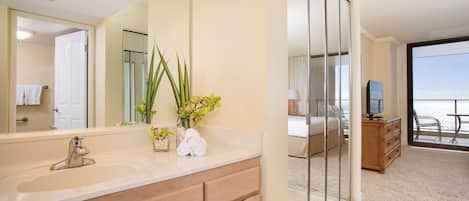 Une salle de bain moderne avec un grand miroir, un lavabo et un vase de fleurs.