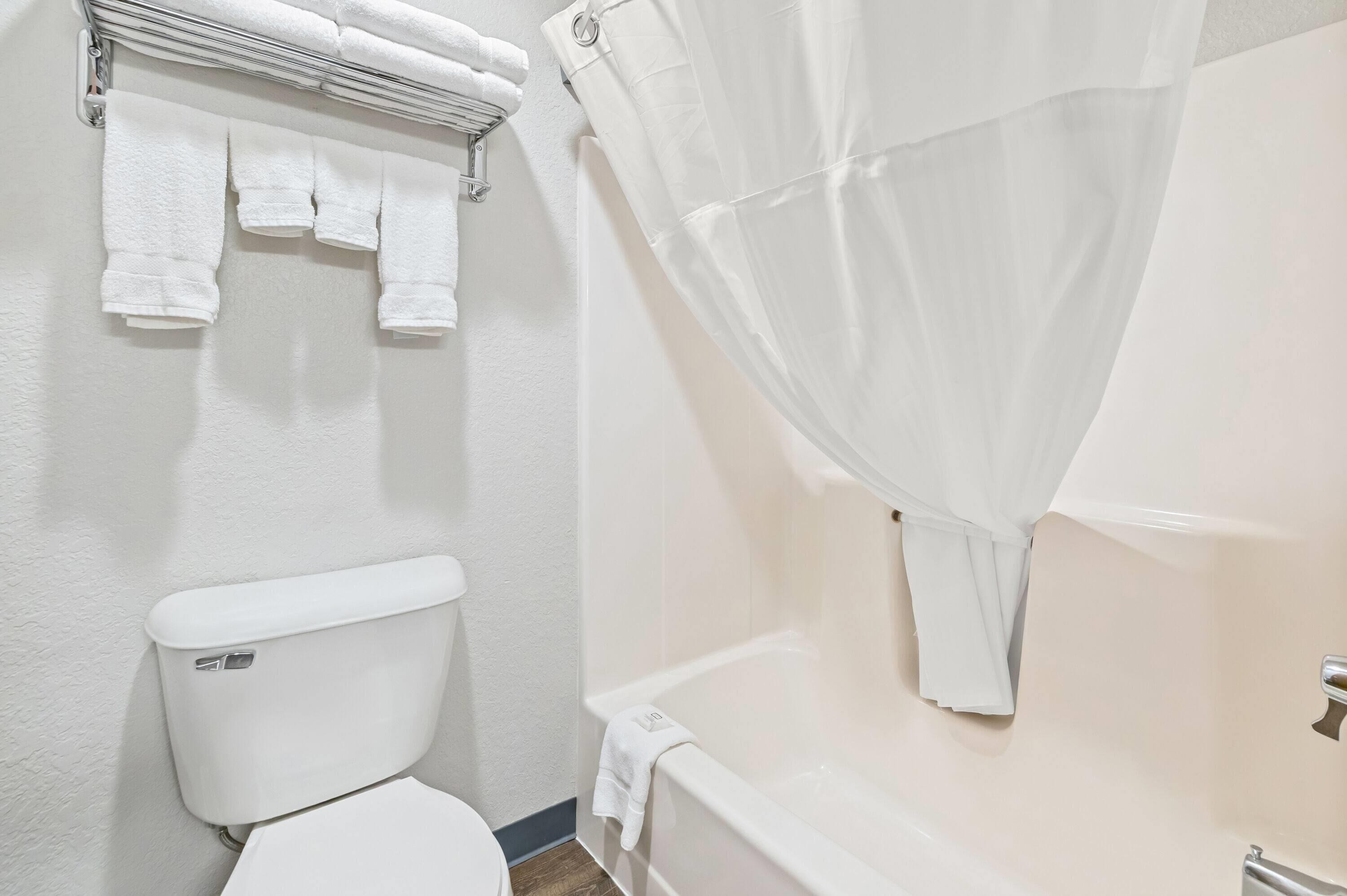 Un baño con inodoro, bañera y cortina de ducha.