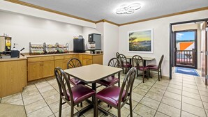A dining area with a table and chairs, a coffee machine, and a television. - Days Inn by Wyndham Wall (Wall)