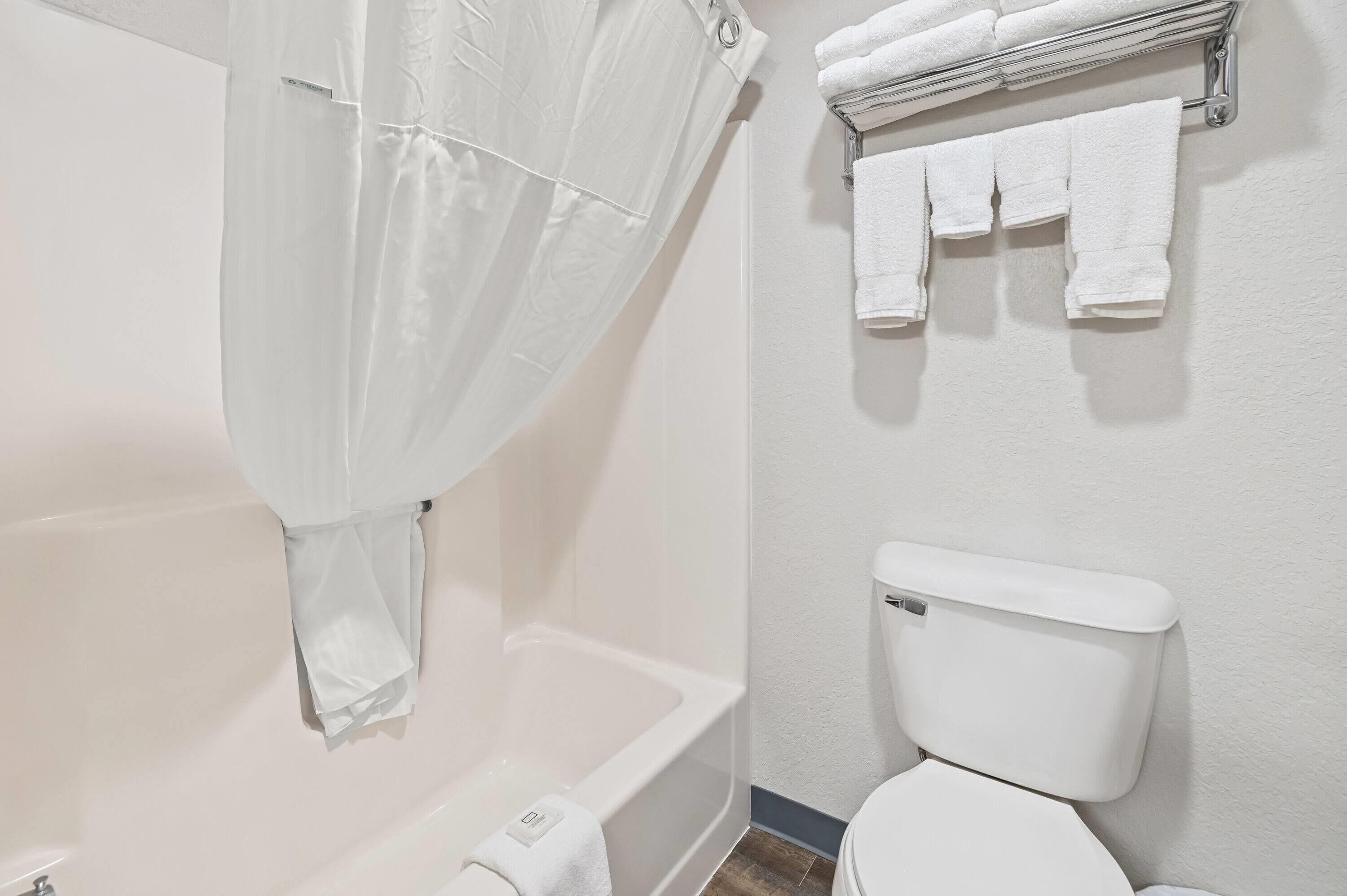 A bathroom with a bathtub, toilet, and a towel rack with towels.