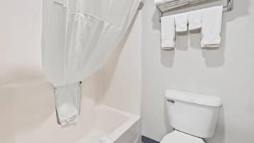 A bathroom with a bathtub, toilet, and a towel rack with towels.
