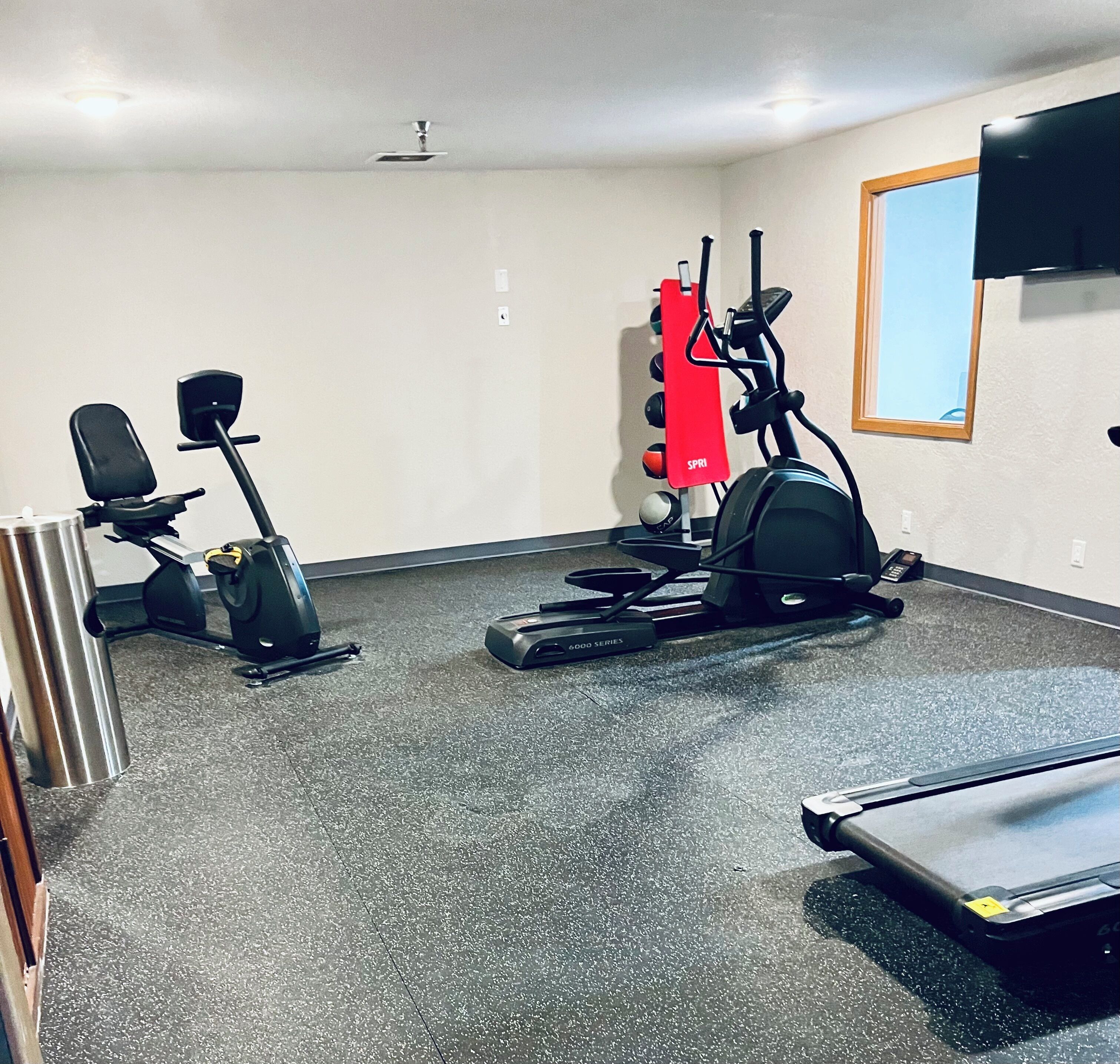 A gym with stationary bikes, a treadmill, and a red exercise machine.