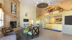 Un'ampia zona giorno con camino, posti a sedere e un soffitto in legno con decorazioni.
