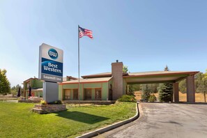 A Best Western Sawmill Inn with a clear blue sky, a flag, and a well-maintained lawn.