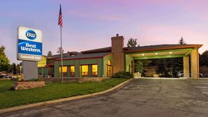 Un Best Western Sawmill Inn con un edificio verde, un'area di parcheggio coperta e una bandiera.