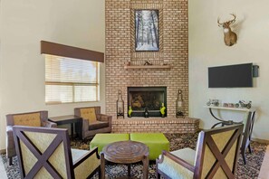 A cozy living room with a brick fireplace, green ottomans, and a mounted TV.