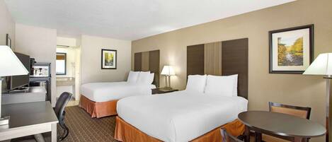 A hotel room with two beds, a desk, a chair, a table, and a lamp.