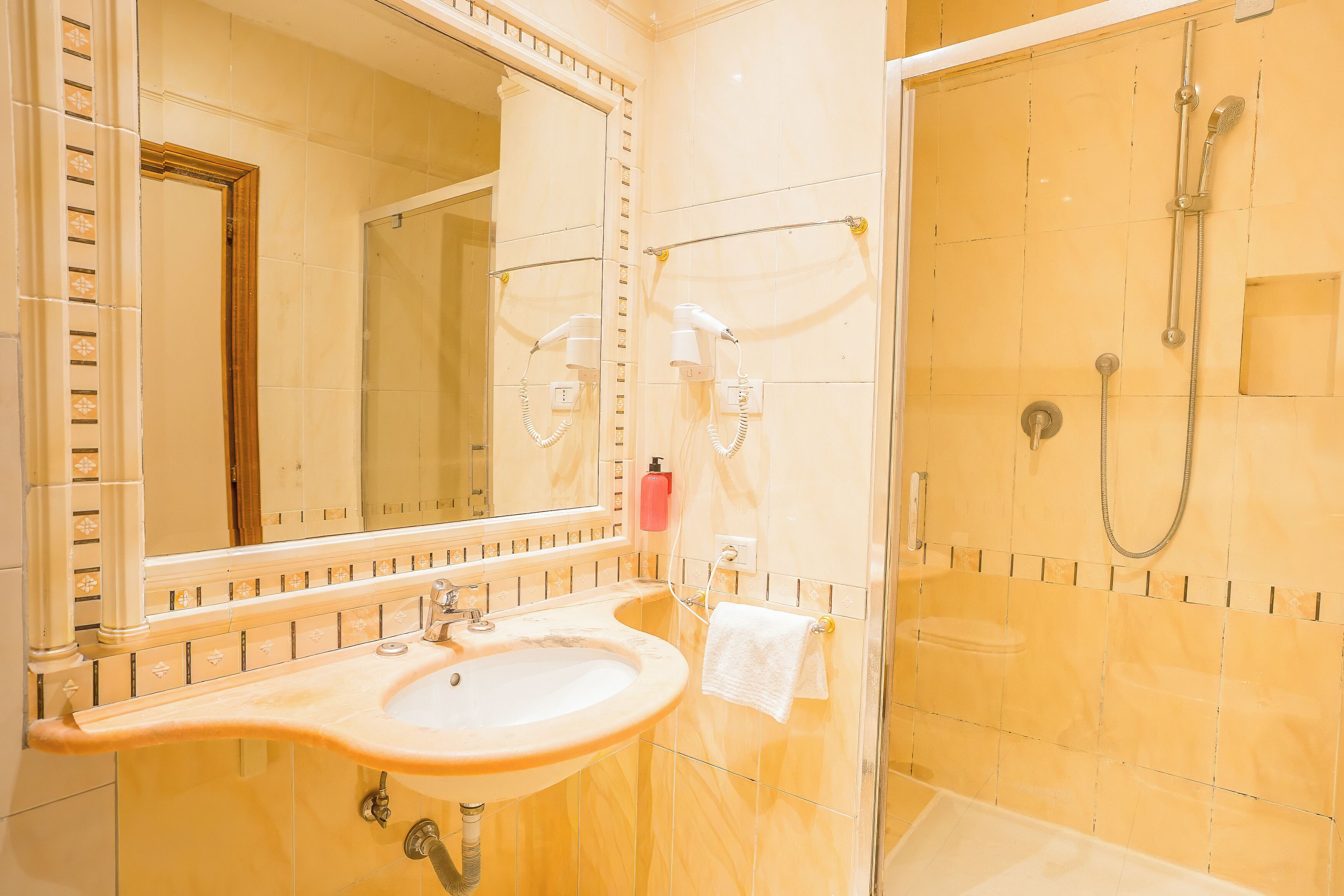 A bathroom with a sink, mirror, and shower.